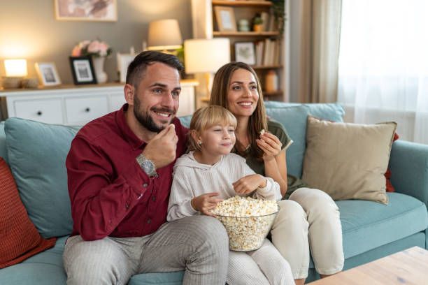 Family eating popcorn and enjoying HD movie streaming on IPTV at home