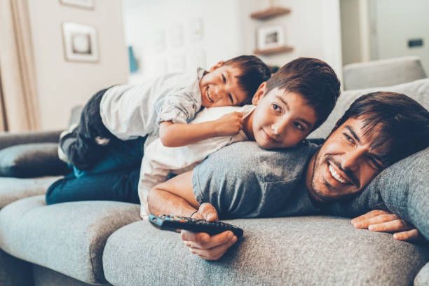 Father and sons watching IPTV streaming together on a home television